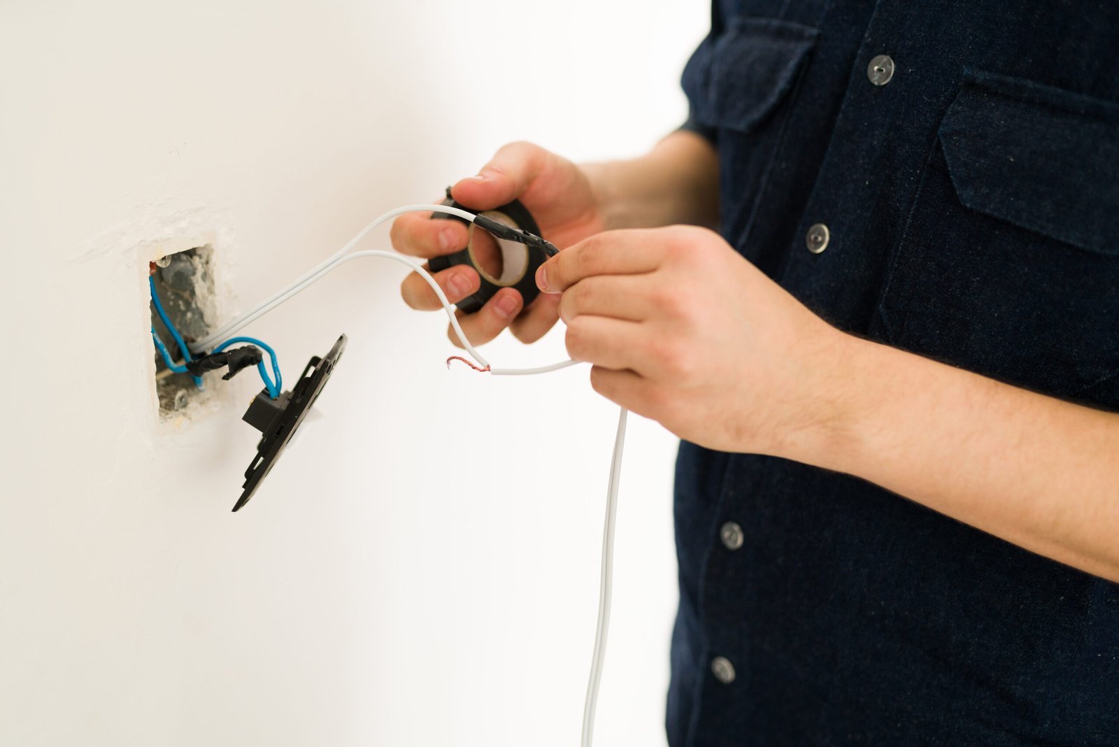 Close up of the hands of a young man hands repairing the broken switch and doing home renovations